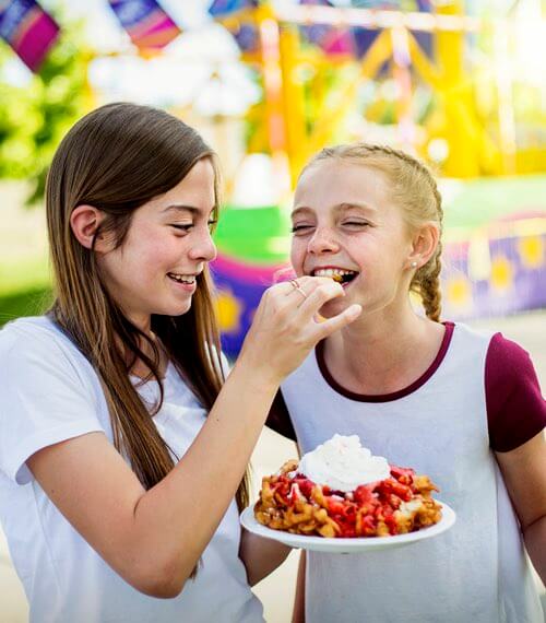 Girls Eating a Funnel Cake With Strawberry Sauce