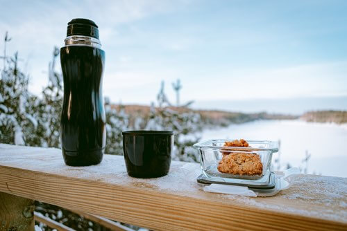 Thermos and Homemade Rolled Oat Cookies on a Deck Railing