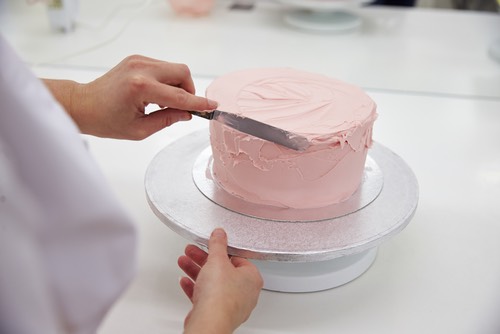 Smoothing the Pink Frosting on a Round Homemade Cake