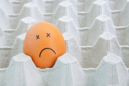 Brown Egg with Sad Face Alone in an Egg Carton